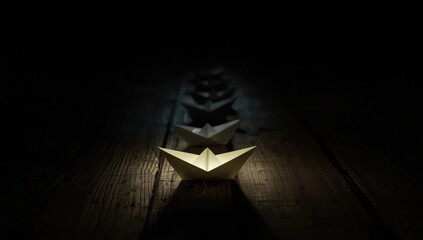 Illuminated paper boat on wooden surface guiding fleet through darkness, leadership focus