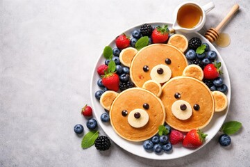 Bear design pancakes served with colorful berries and honey on a subtle gray concrete backdrop providing space for recipe sharing