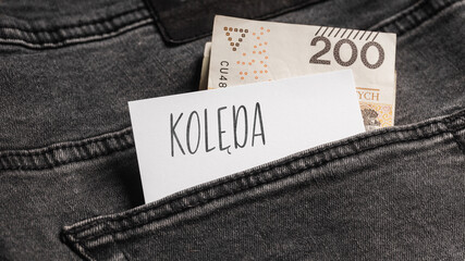 White card with a handwritten inscription "", inserted into the pocket of gray pants jeasnow, next to Polish banknotes PLN (selective focus), translation: