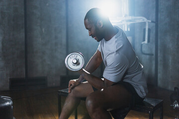 Fitness workout in gym. African American man bodybuilder picking up dumbbells in gym. Workout weight training biceps muscles with dumbbell in fitness club. Man doing sports exercise. Healthy lifestyle