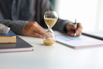 Selective focus on sand clocks. Businessman working at office desk. Time management concept. © Supitnan