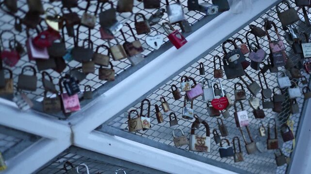 Numerous love locks hanging on a bridge railing capturing romantic tradition couples attach padlocks symbolizing love Valentine's Day and city scenery