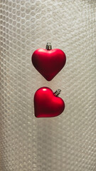 Two Red Heart Ornaments on Bubble Wrap Texture for Valentine's Day or Christmas