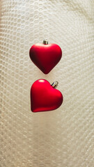 Two Red Heart Ornaments on Bubble Wrap Texture for Valentine's Day or Christmas