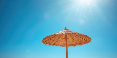 Detailed view of a straw beach umbrella under a clear sky, ideal for editorial header background, summer season