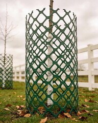 A green metal fence surrounds a tree