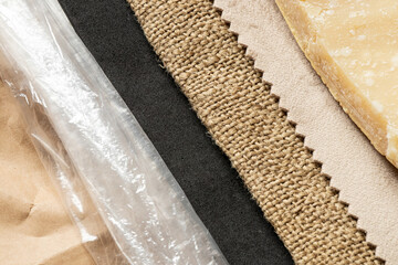 A collage of different textures in vertical stripes, including paper, a clear bag, a dark porous...
