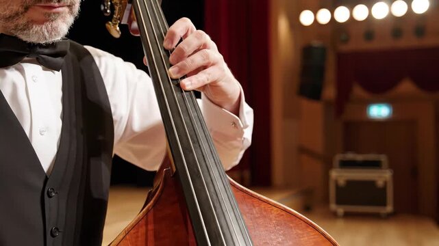 Musician playing double bass on stage. Man's hands on strings of upright bass during a live performance. Classical music and jazz concert concept