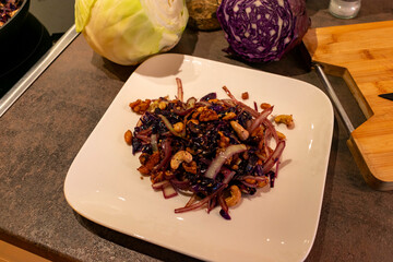 Pfannengericht aus Rothkohl, Wei&szlig;kohl und N&uuml;ssen angerichtet auf einen wei&szlig;en Teller