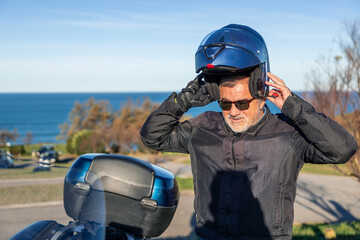 Biker senior man fastening helmet before a motorcycle ride