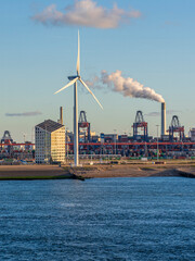 Wind turbine and port cranes contrasting green energy and industry in Rotterdam