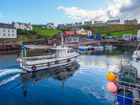 Fishing boat leaving St Abbs harbor in Scotland