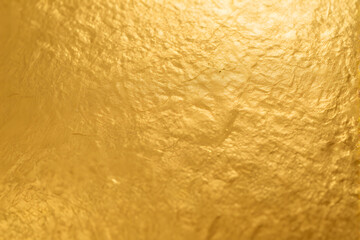 A close-up shot of textured gold-colored surface with rough uneven cracks and crevices creating depth