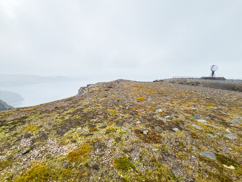 The north cape globe monument perched on a cliff with a misty sea view in norway