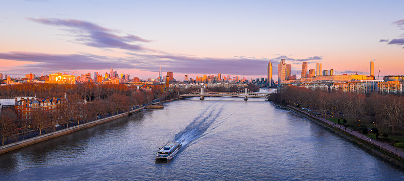 River Thames by Battersea Park with boat and London UK skyline at dusk