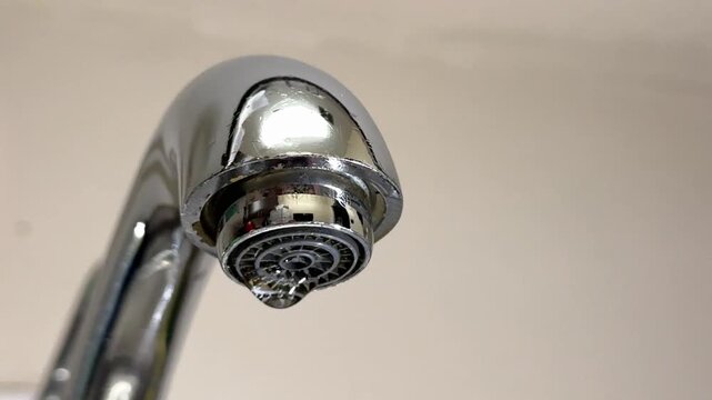 Water Drop From Faucet Aerator.Close-up of a faucet aerator with a falling water drop, symbol of water leak, waste, conservation, saving water, household plumbing problem and sustainability concept.
