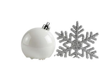 Macro close-up of a matte white christmas bauble beside a shimmering silver snowflake nestled in soft crystalline snow against a transparent high-key background, minimalist holiday elegance concept