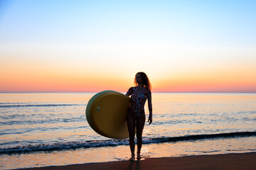 Young woman standing on beach with paddle sup boards during summer vacation