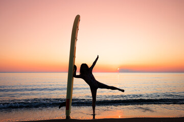 Young woman standing on beach with paddle sup boards during summer vacation