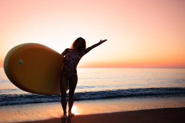 Young woman standing on beach with paddle sup boards during summer vacation