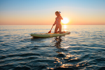 Young woman walking on stand up paddle sup boards by the sea during summer vacation