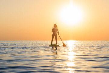 Young woman walking on stand up paddle sup boards by the sea during summer vacation