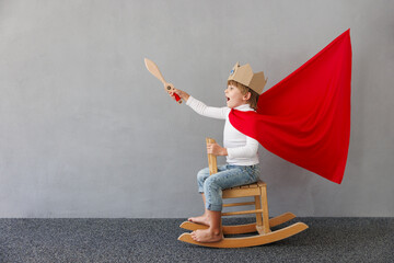 Funny child pretend to be knight. Happy kid having fun at home