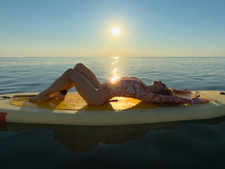Young woman walking on stand up paddle sup boards by the sea during summer vacation