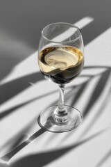 Fototapeta premium Elegant white wine glass on a white background with dramatic shadows and light