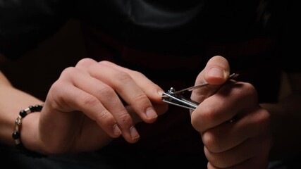 Close up young male hands using nail clippers to trim fingernails. Personal grooming and self care. Male manicure done independently. Regular hand care and hygiene routine.