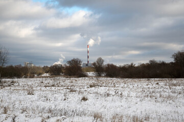 Winter landscape with the chimney of a thermal power plant in the background.
