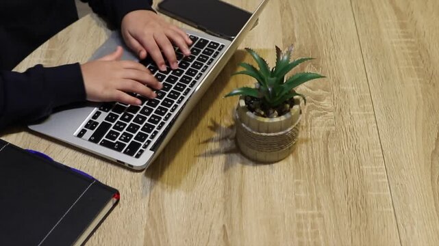 Young child typing on a laptop at home, browsing the internet under parental controls to illustrate online safety, cybersecurity, privacy and protection from cyberbullying