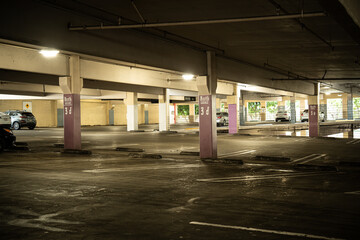 Empty parking garage level with concrete pillars and parked cars in the distance © Tom