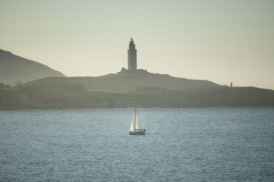 paisaje en el mar con un barquito y la torre de hercules 