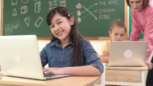 Smart asian girl looking at camera while coding engineering prompt. Multicultural student learning about generated AI while teacher teaching about system or checking classwork at STEM class. Pedagogy.