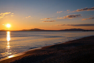 Obraz premium Peaceful sunrise over coastal beach with pier and hills