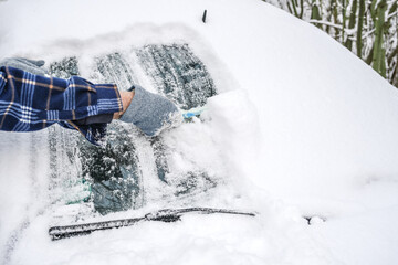 Hand sweeping off a thick layer of snow on the windshield of a car, driving preparation, dangerous...