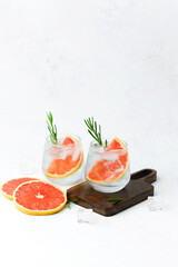  Cold grapefruit cocktail with rosemary and ice served with fresh citrus slices on white background