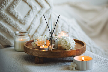 Aroma diffuser, burning candle, blooming hyacinth flowers and perfume on wooden bamboo tray. Cozy home decor, hygge and aromatherapy concept. Comfortable atmosphere, spring delicious fresh smell