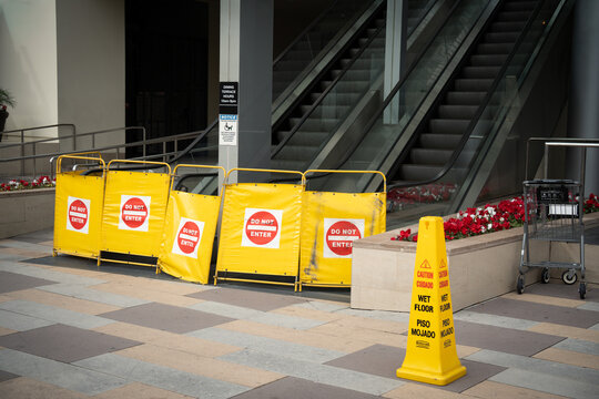 Yellow caution signs and wet floor cone block access near escalators