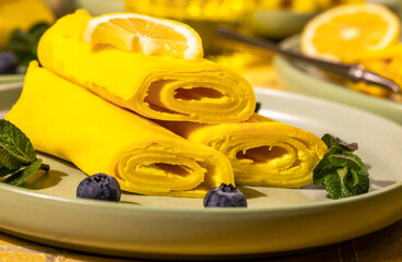 Rolled crepes with lemon, blueberries, and mint on plate
