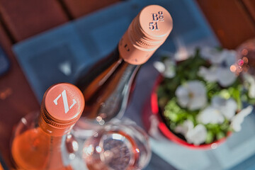 Zwei Flaschen gekühlter Roséwein auf einem rustikalen Holztisch neben Blumen, Sommerabend in der...