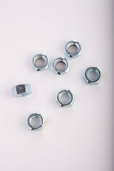 Assorted steel hex nuts on white background for industrial hardware supply and mechanical engineering. Various sizes of metallic fasteners for bolt security construction and technical assembly