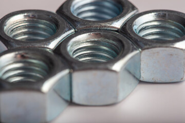 Hexagonal steel nuts macro industrial hardware group for mechanical engineering and construction projects. Close-up of silver metallic fasteners used for secure bolt connection and assembly