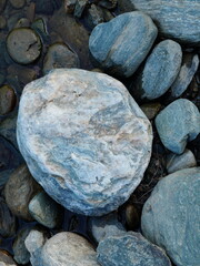 Closeup of natural eroded stones with rough texture and bluish color on side of the river