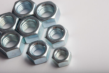Assorted steel hex nuts on white background for industrial hardware supply and mechanical engineering. Various sizes of metallic fasteners for bolt security construction and technical assembly