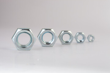 Steel hex nuts stack tower on white background for industrial business concept and construction balance. Vertical row of metallic fasteners representing strength stability and engineering precision