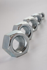 Hexagonal steel nuts macro industrial hardware group for mechanical engineering and construction projects. Close-up of silver metallic fasteners used for secure bolt connection and assembly