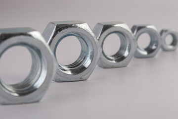 Steel hex nuts stack tower on white background for industrial business concept and construction balance. Vertical row of metallic fasteners representing strength stability and engineering precision