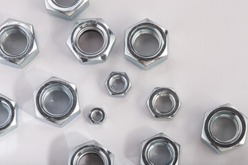 Assorted steel hex nuts on white background for industrial hardware supply and mechanical engineering. Various sizes of metallic fasteners for bolt security construction and technical assembly